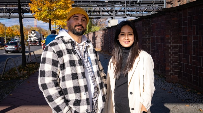 An image of a man and a woman standing on a city street facing the camera. 