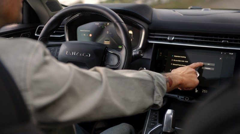 An image looking over a driver’s shoulder as the reach out to interact with the touchscreen display inside a Lynk & Co car.